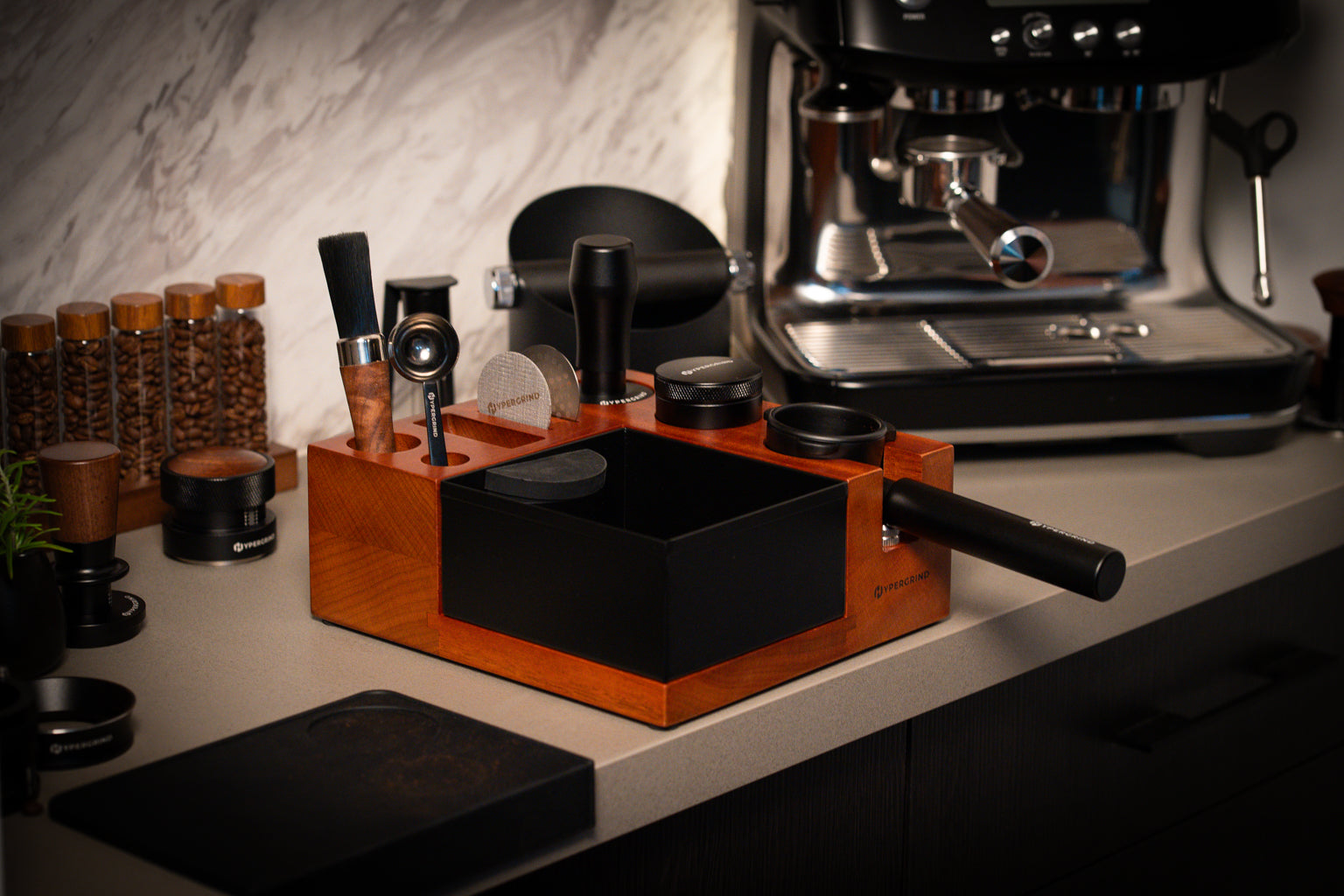 Hypergrind Tamping Station Kit with Portafilter, Tamper, Distributor, Puck Screens, Spoon and Brush, on a kitchen bench.