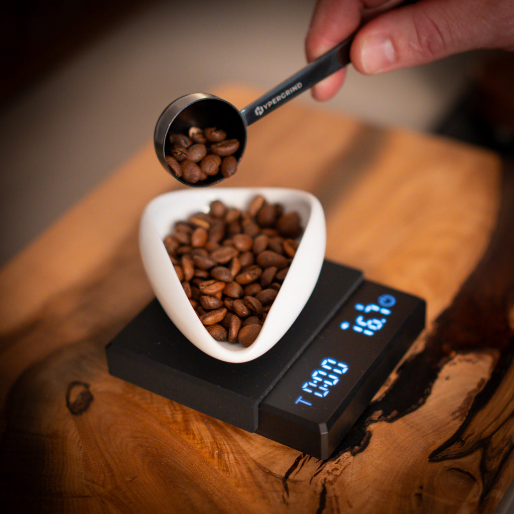 Intelligent Coffee Scales (Black) with a weighing dish and coffee beans on top.